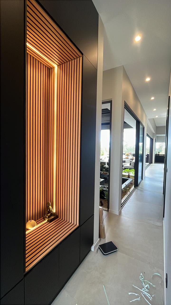 Bedroom corridor with black wardrobes and a lit oak niche