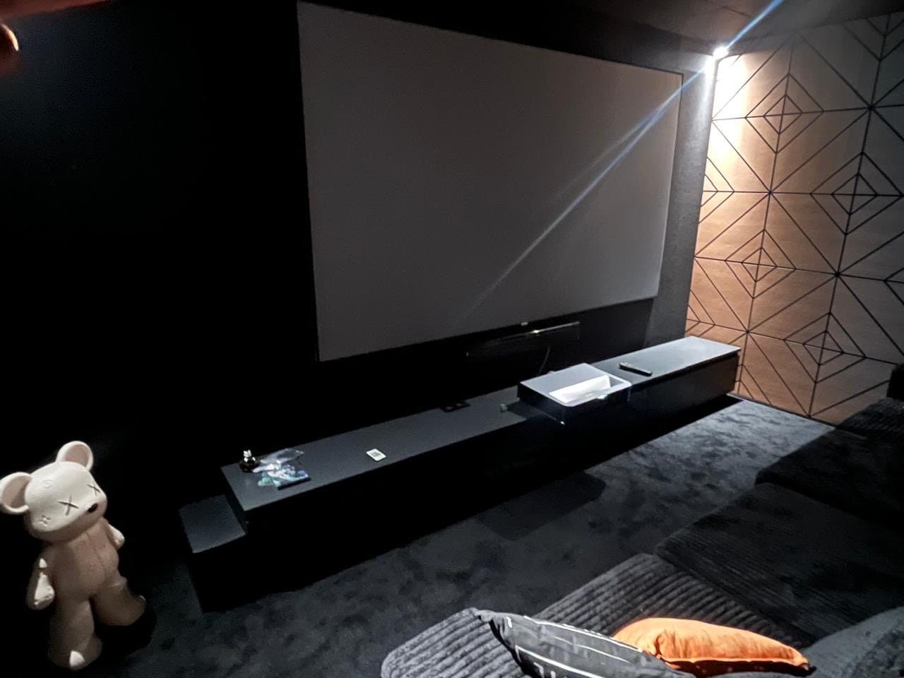 Cinema screen with laser projector on a low console