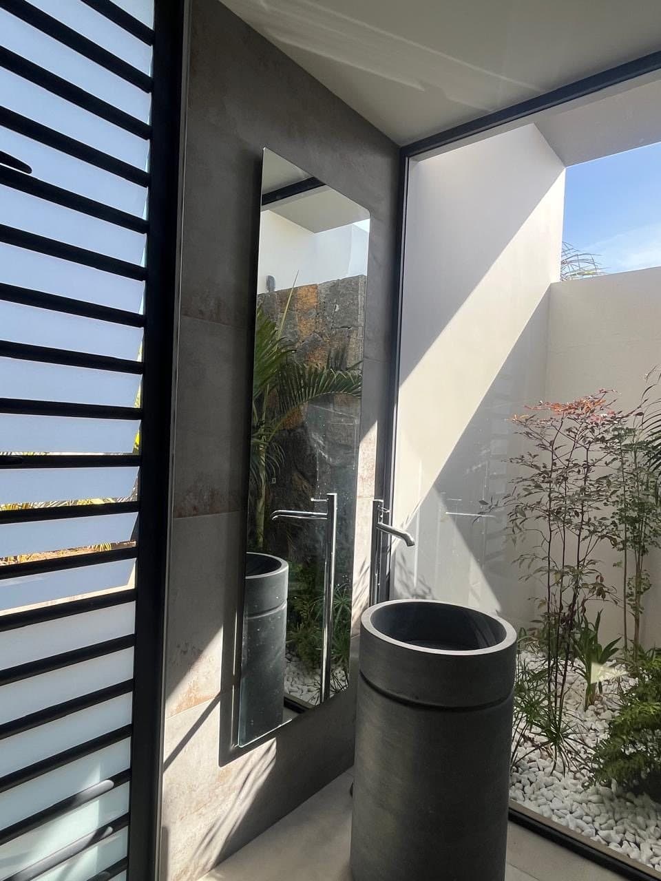Bathroom with concrete column basin and view onto a private patio