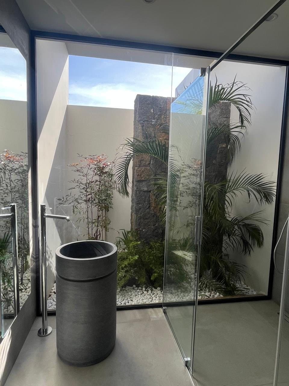 Bathroom opening onto a walled patio with a stone column and white pebbles