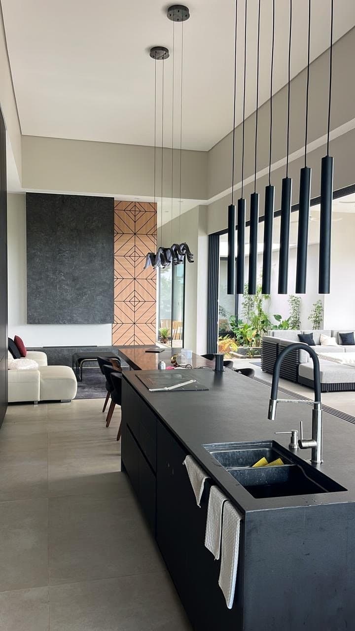 Living room with cream leather sofa, black kitchen island and seven pendant lights