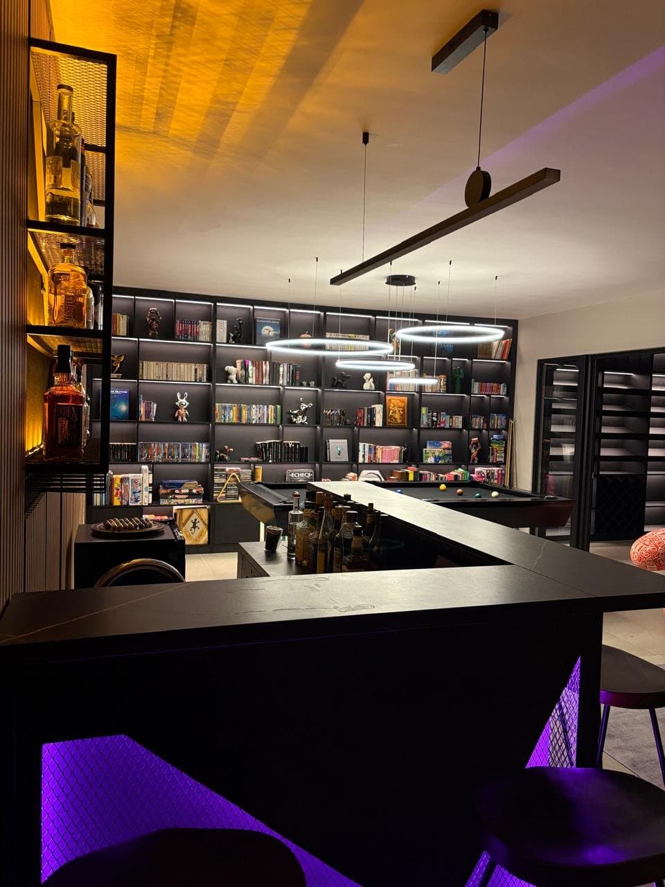 Backlit library wall with books, games and figurines