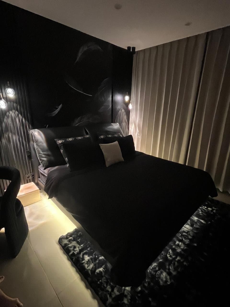 Black bedroom with feather fresco headboard and under-bed lighting